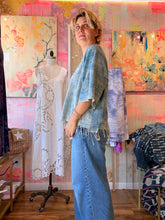 Load image into Gallery viewer, Side view of a loose lightweight indigo-dyed shirt with fringe hem, modeled indoors