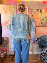 Load image into Gallery viewer, Back view of a loose lightweight indigo-dyed shirt with fringe hem, modeled indoors
