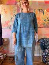 Load image into Gallery viewer, Close front view of a West African indigo-dyed shirt with side slits and fringed lower edge, modeled indoors