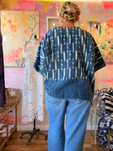 Load image into Gallery viewer, Front view of a deep blue West African indigo-dyed shirt with contrasting linear pattern and fringed hem, modeled indoors