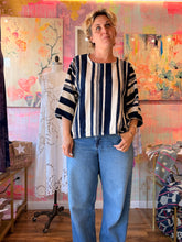Load image into Gallery viewer, Back view of a West African indigo-dyed shirt with bold navy and cream vertical stripes and wide sleeves, modeled indoors