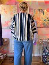 Load image into Gallery viewer, Alternate front view of a relaxed West African indigo-dyed shirt with bold contrasting stripes and wide sleeves, modeled indoors