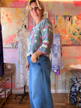 Load image into Gallery viewer, Side view of a soft thin West African indigo-dyed shirt with pink stripes and patterned sleeves, modeled indoors