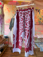 Load image into Gallery viewer, Front of hand-dyed vintage tablecloth pants with a berry-red hibiscus floral column down each leg on lavender-white