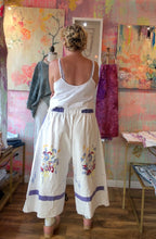 Load image into Gallery viewer, Back of white vintage tablecloth pants with wildflower bouquets and lavender hem bands