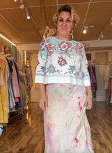 Load image into Gallery viewer, Front view of the vintage tablecloth shirt, showing its pink floral print, pale blue ground, and wide hem border